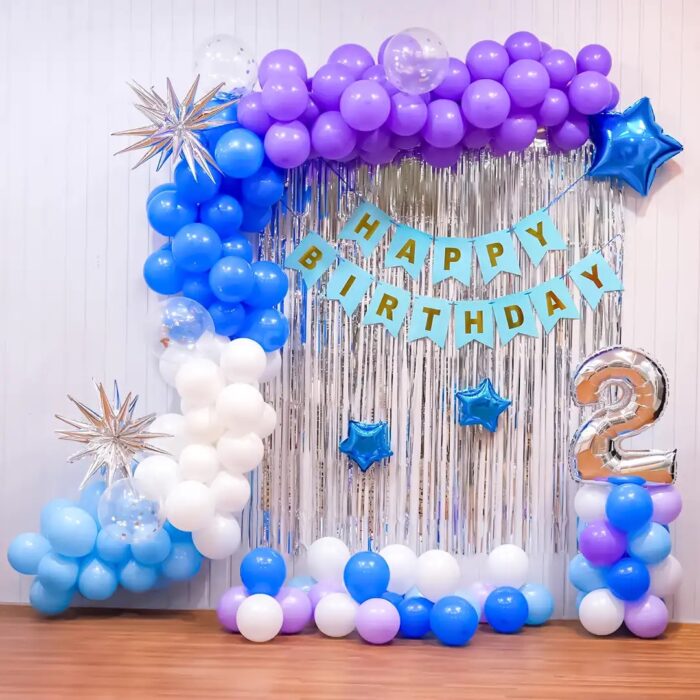 Elegant blue and purple birthday decor with a balloon arch, confetti balloons, and silver star accents.