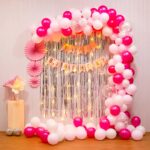 Elegant pink and silver balloon arch for birthday celebration.